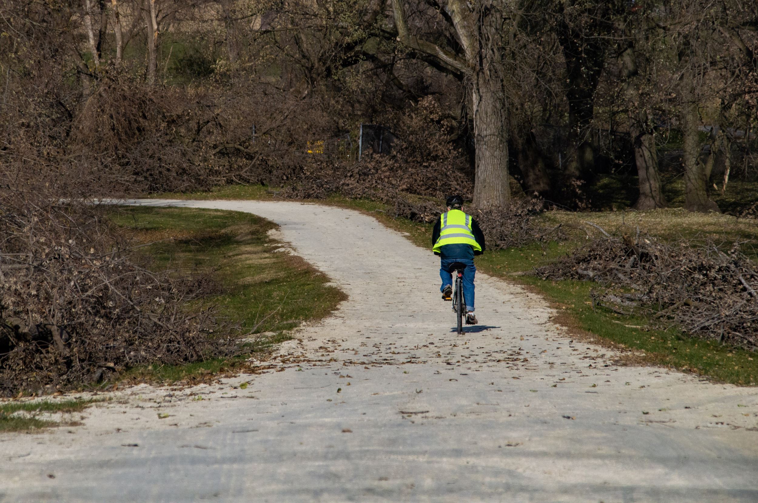 Man in sanitation jacket rides a bike down a path