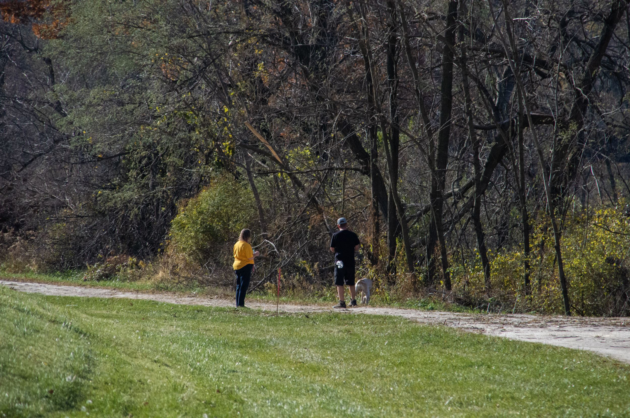 Two people standing on a trail with their dog