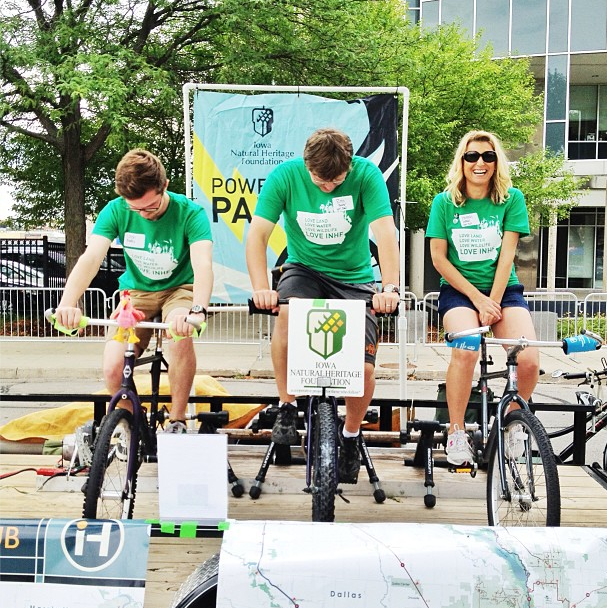 INHF's bike generator was a hit at the Des Moines stop of RAGBRAI, where it supplied the energy for a stereo and cell phone charging station.  Pictured (from left to right): Trails Intern, Josh Mades; Land Projects Associate Ross Baxter; and Communications Director Hannah Inman.